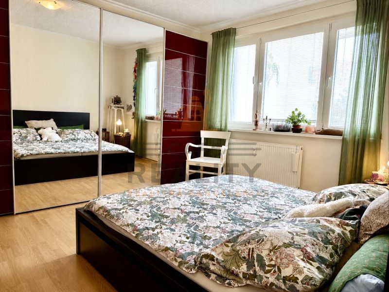 Bedroom with a large wardrobe, bed, and wooden decor flooring in a 3-room apartment.