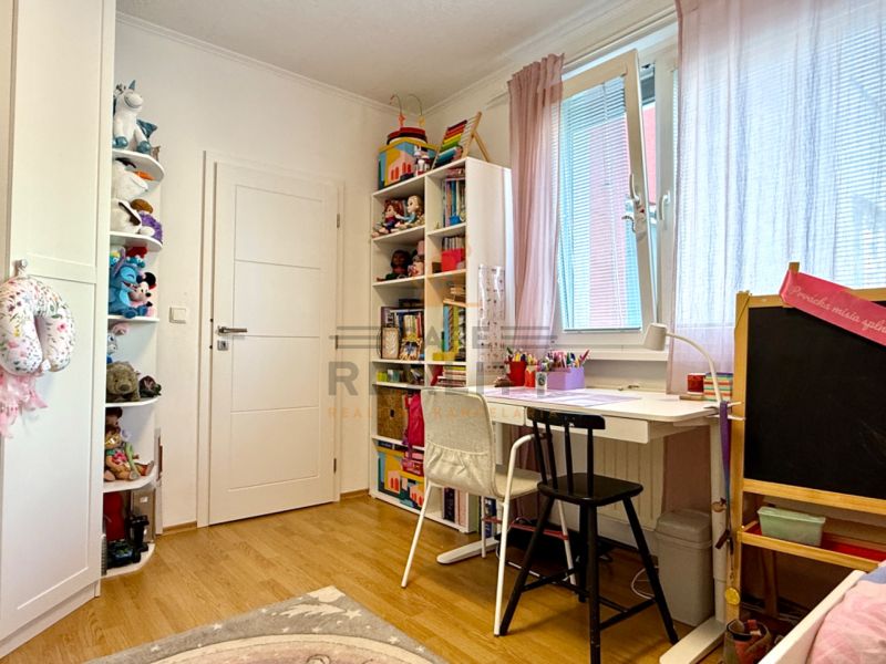 Children's room in a 3-room apartment with a wooden decor floor and a desk.