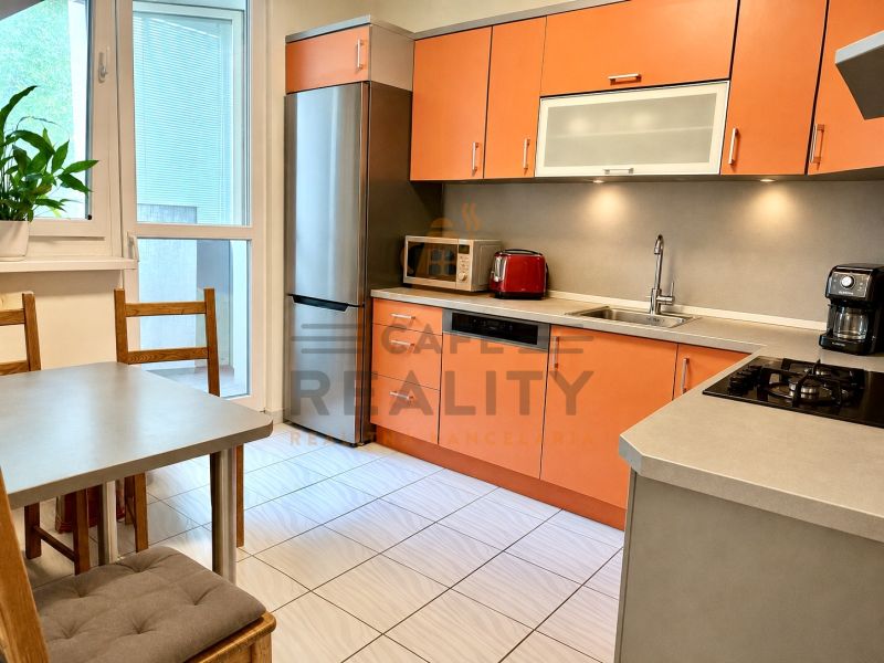 A kitchen in a 3-room apartment with orange cabinets and modern appliances.