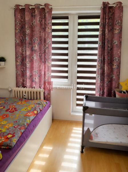 Children's room with curtains and a bed in a 2-room apartment, floor with wood decor.