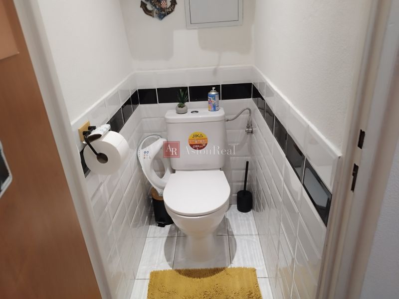 Bathroom in a 2-room apartment with ceramic tiles and white sanitary ware.