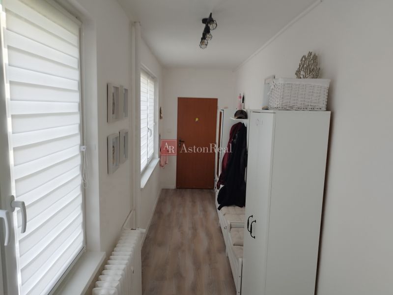 A narrow corridor with a wardrobe, a floor with a wooden decor, and white walls in a 2-room apartment.
