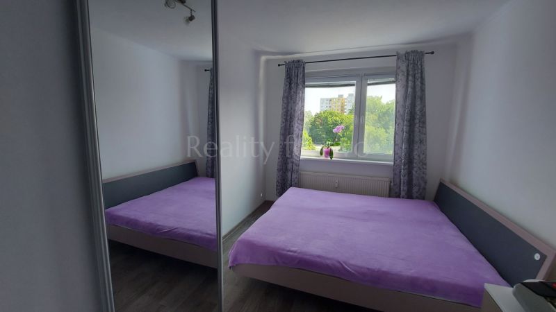 Bedroom in a 2-room apartment with a bed and a view from the window.