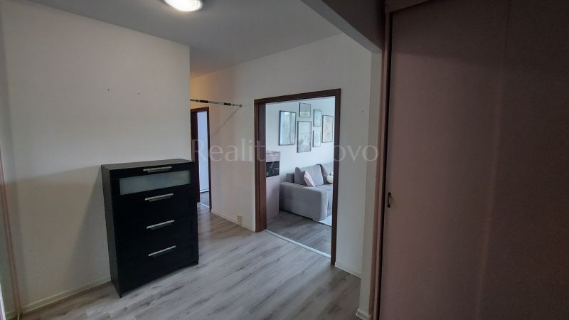 The entrance hall of a 2-room apartment with a chest of drawers and a floor with a wooden decor.