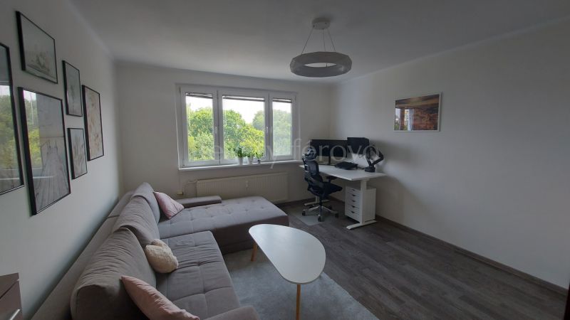 Living room in a two-room apartment with a corner sofa, a coffee table, and a desk.