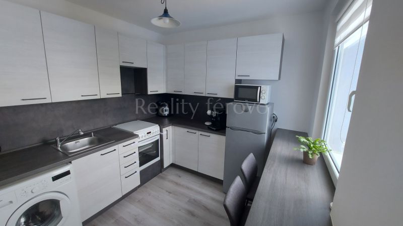 A kitchen in a 2-room apartment with white cabinets, a microwave, and appliances.
