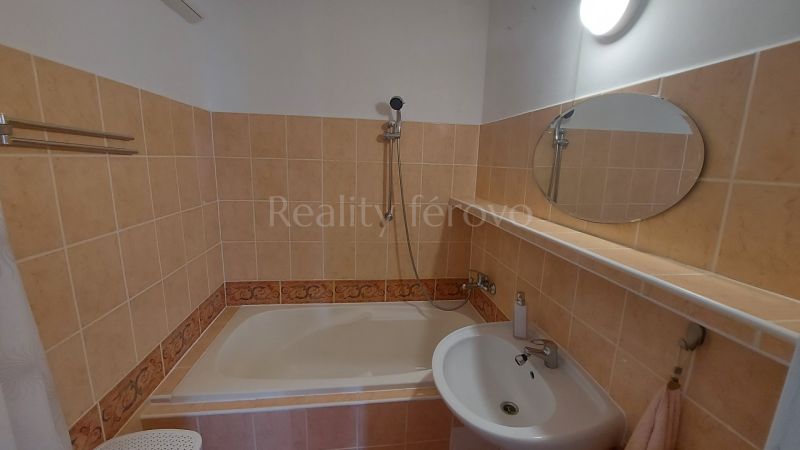 Bathroom in a 2-room apartment with a bathtub, sink, and simple mirror.