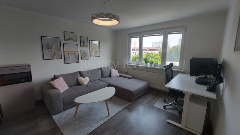 Living room with a corner sofa, a desk, and a floor with a wooden decor.