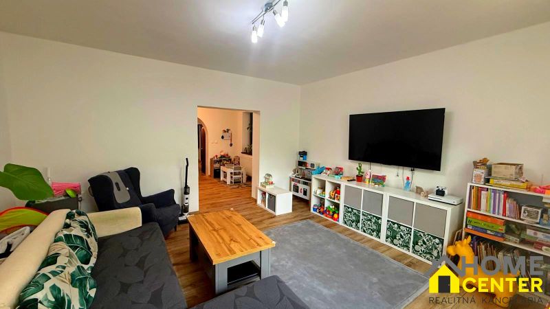 Living room of a family house with a television, carpet, cabinets, and sofas, floor with wooden decor.