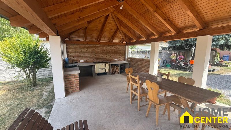 Exterior of a family house in Iža with a wooden shelter, table, and chairs.
