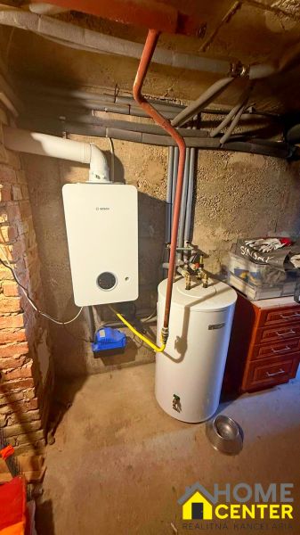 Boiler and water heater in the utility room of a family house with a brick wall.