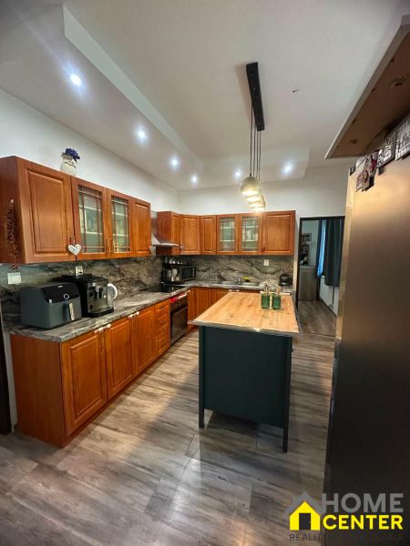 Interior of a family house with a kitchen island, wooden cabinets, and a floor with a wooden decor.