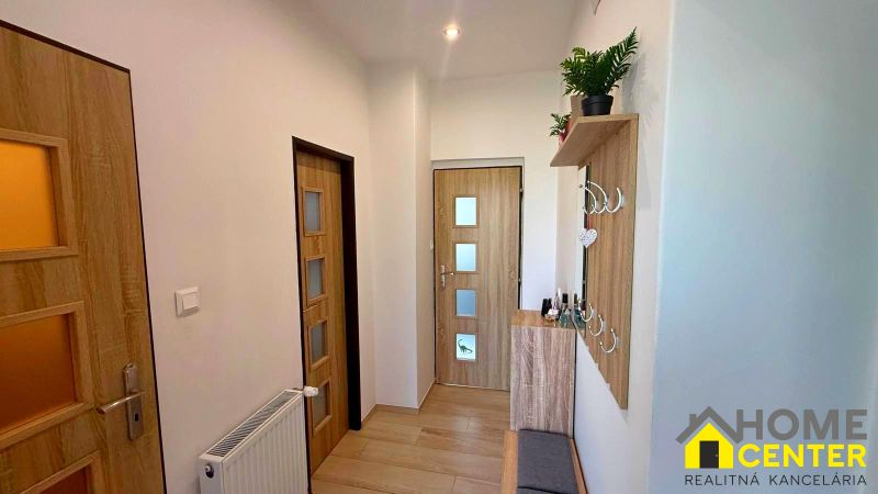A hallway in a family house with a wooden decor floor, wooden doors, and a coat rack.