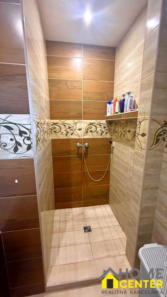 Shower enclosure in a family house with ceramic tiles and decorative pattern.