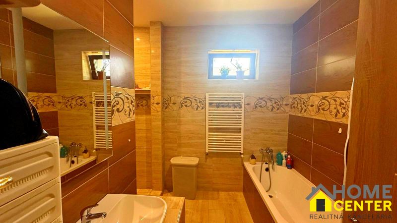 A bathroom in a family house with ceramic tiles and a bathtub.