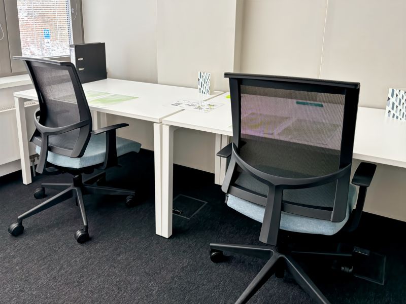 Two office chairs at work desks, black floor with a textile surface.