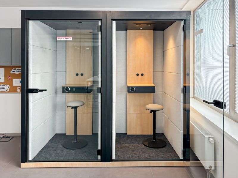 Two telephone booths with wood-decorated floors in offices.