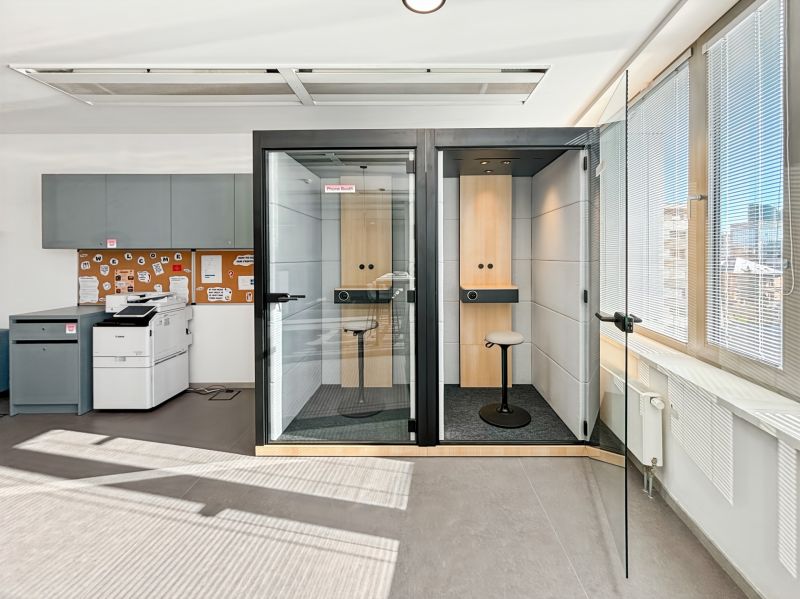 Offices with phone booths and a printer, simple interior with glazing.