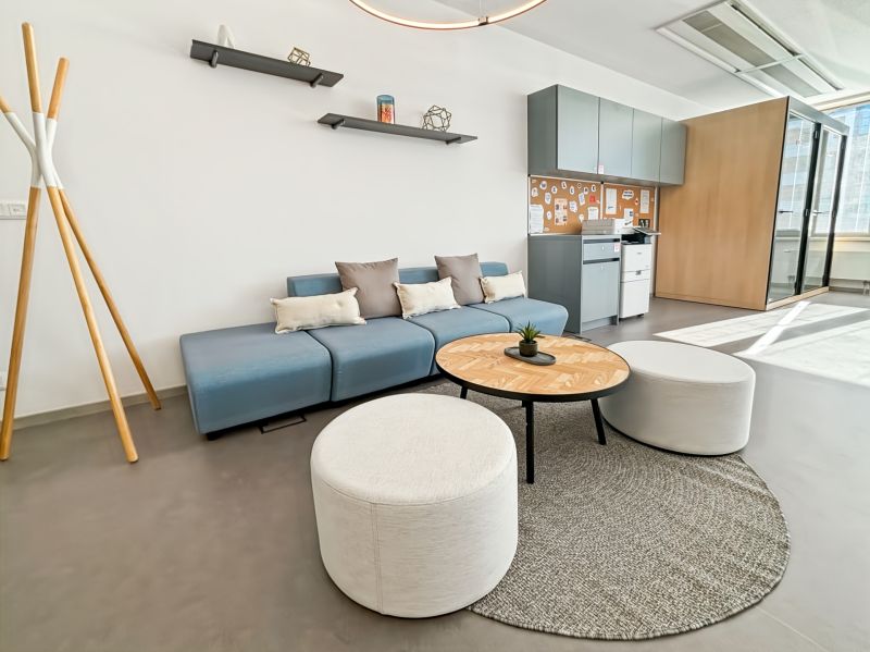 Comfortable office interior seating with a blue sofa, round tables, and hanging shelves.