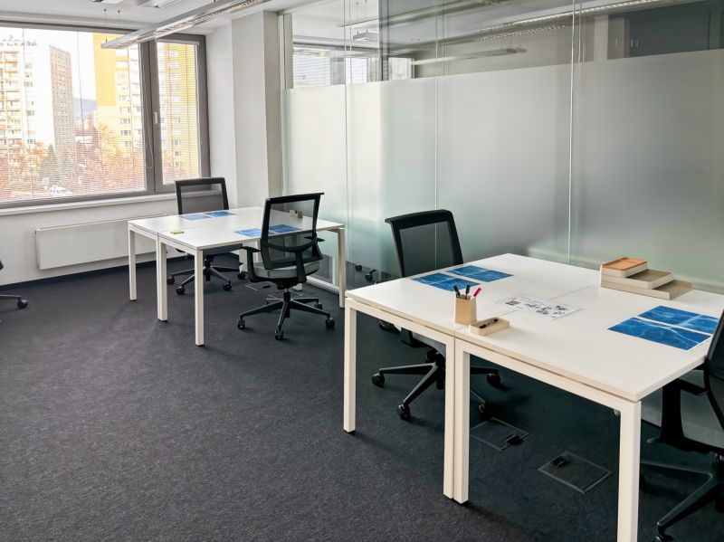 Offices with white desks, comfortable chairs, and a large window.