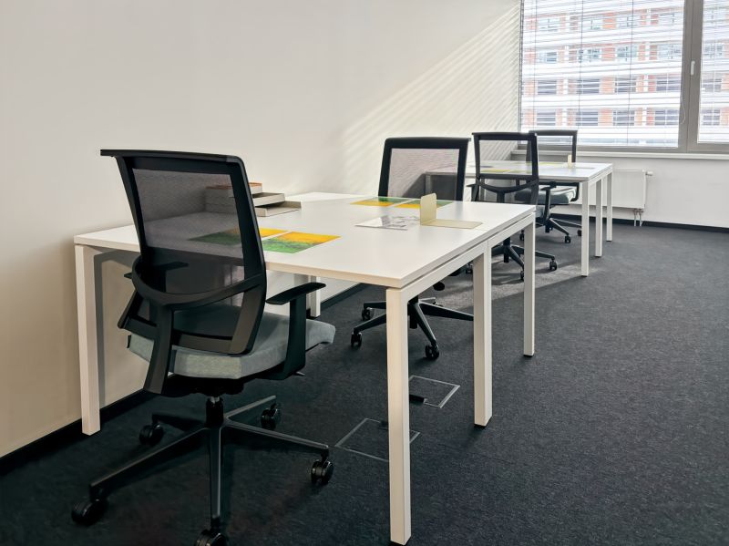 The interior of offices with white desks and black chairs, suitable for work.