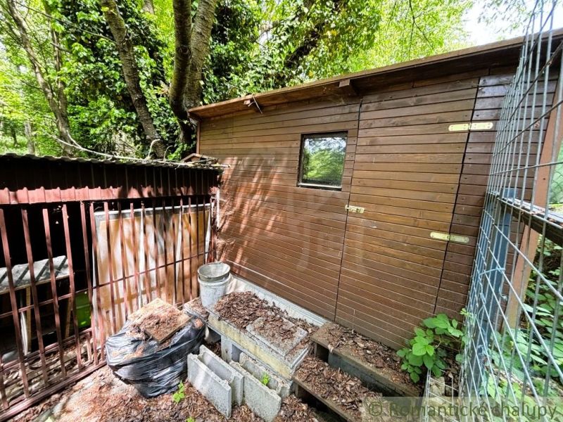 A wooden cottage in Bratislava IV surrounded by a forest and a goose coop.