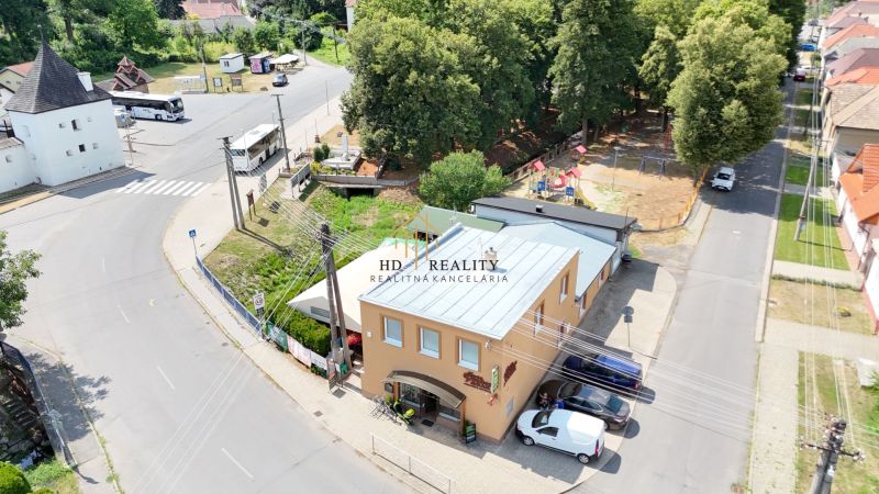 Commercial premises in Divín with a bus stop and surrounding greenery.