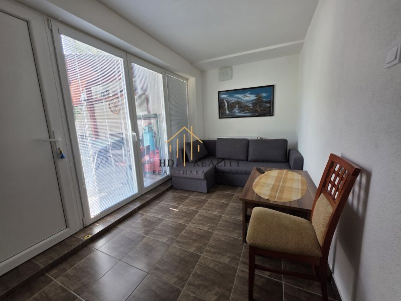 Commercial space with a sofa, table, and chair, tiles imitating wooden decor.