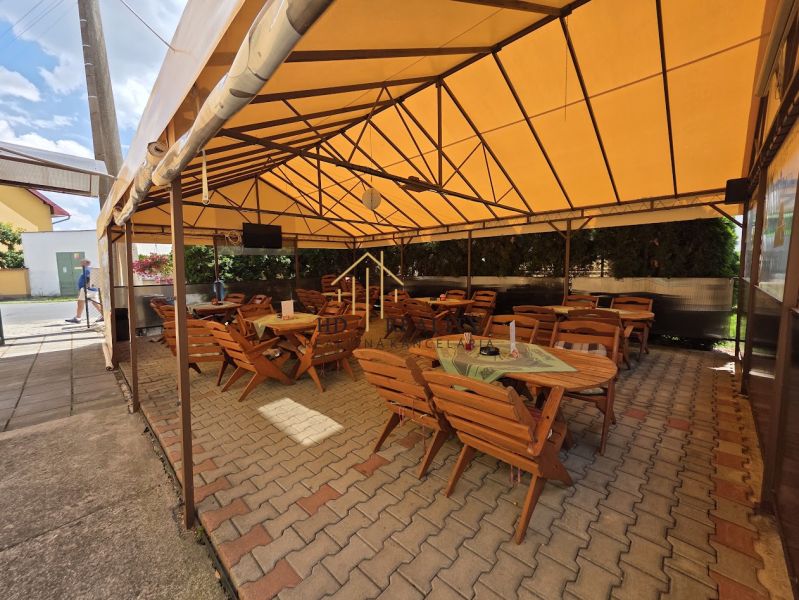 Covered commercial spaces in Divín with wooden tables and chairs on the terrace.
