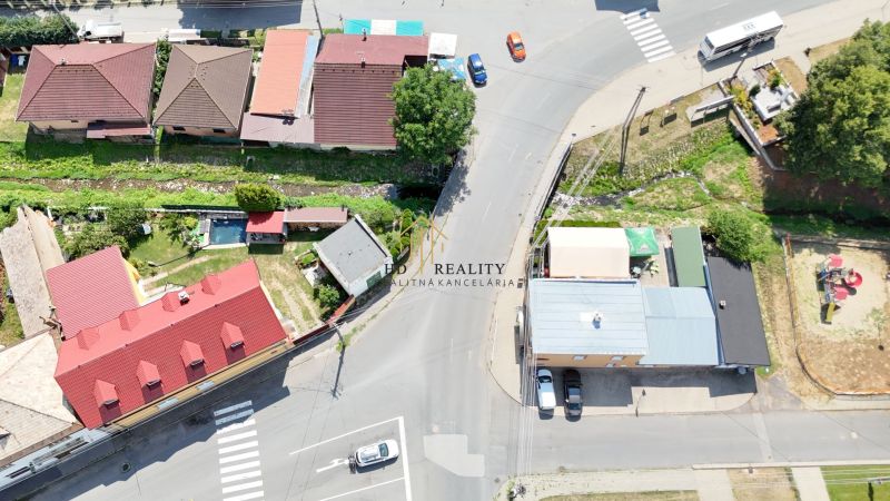 A top view of commercial premises in Divín with steep roofs and an adjacent green plot.