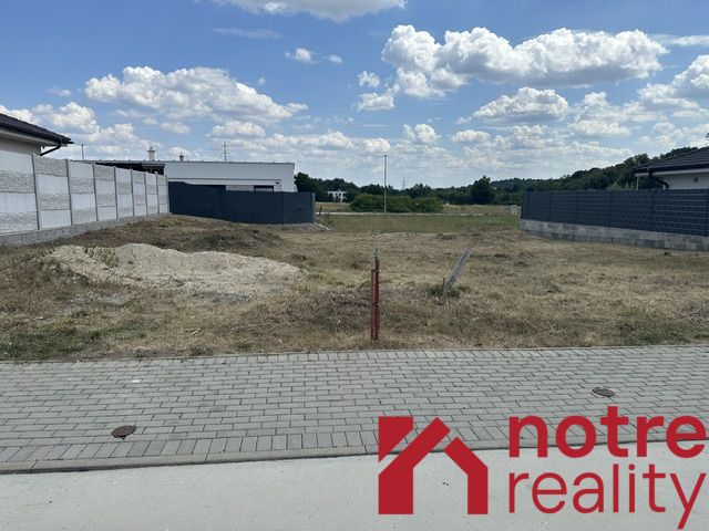 Residential plots in Lučenec, an empty building plot between houses, blue sky.