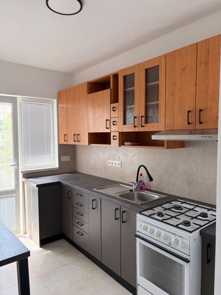A kitchen in a 2-room apartment with a wooden decor floor and a practical kitchen unit.