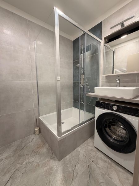 Shower corner and washing machine in the bathroom of a 2-room apartment with ceramic tiles.
