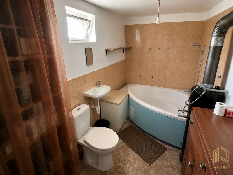 A bathroom in a cabin with a bathtub, sink, toilet, and a window for natural light.