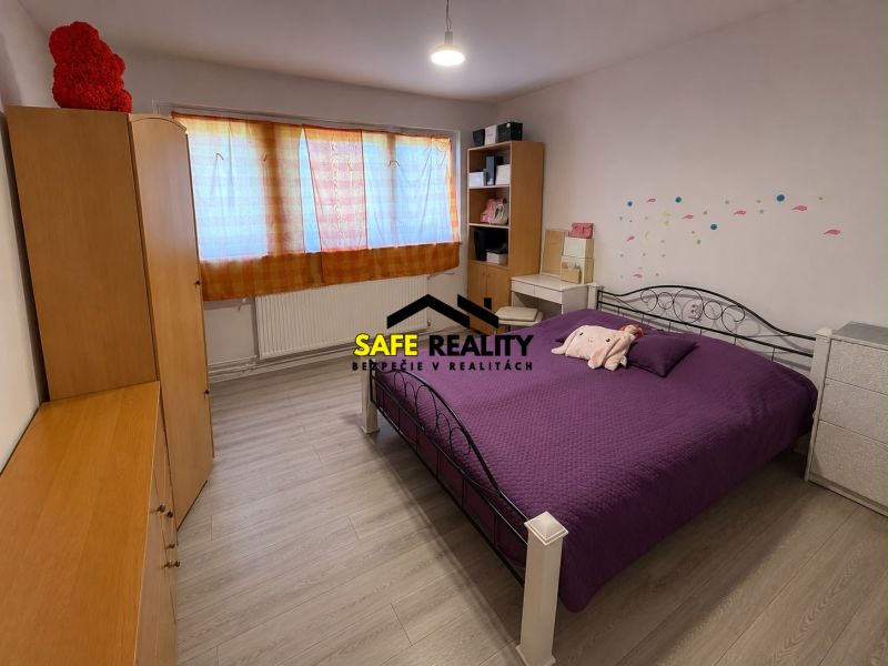 A bedroom in a family house with a bed, wardrobes, and a floor with a wooden decor.