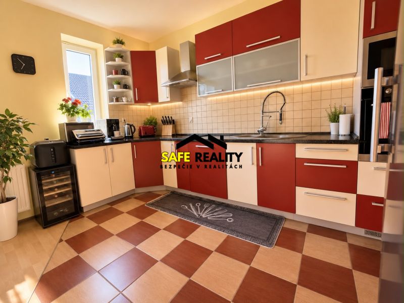 A kitchen in a family house with red and white cabinets, and a wooden decor floor.