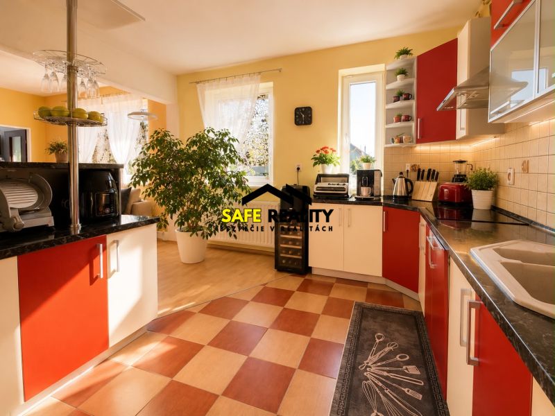 A bright kitchen in a family house with red cabinets and a wood-patterned floor.