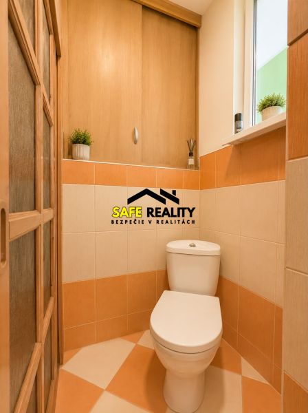 A toilet in a family house with tiled walls and wooden doors.