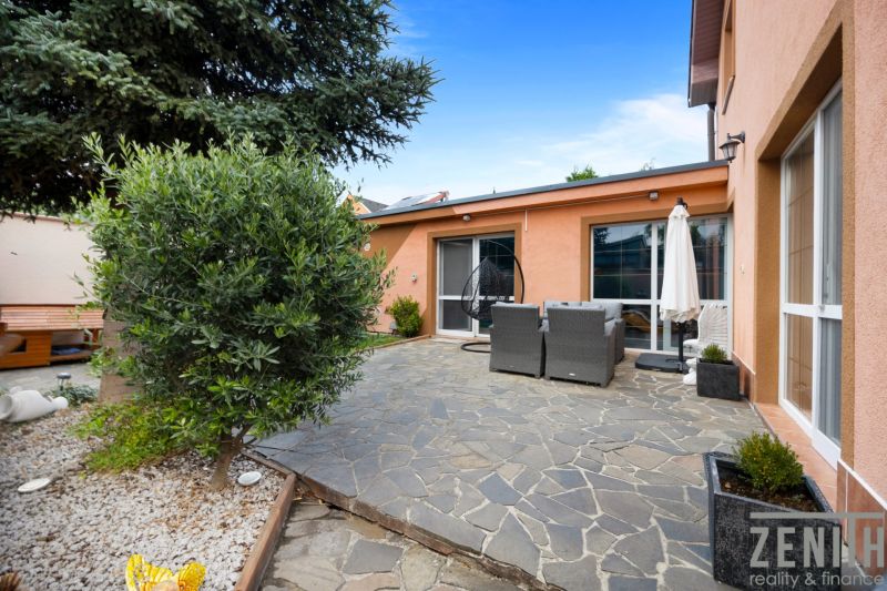 The garden of a family house in Bernolákovo with a stone terrace and outdoor seating.