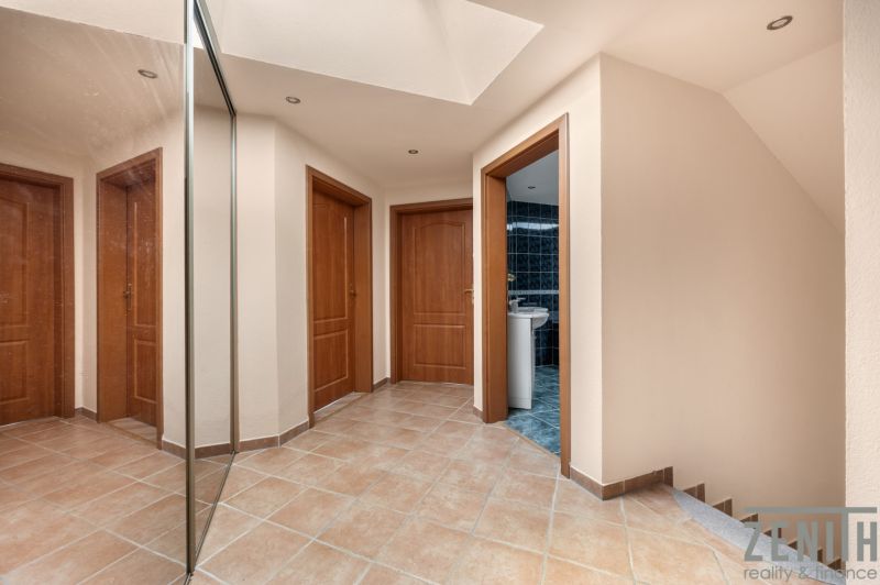 A hallway of a family house with tiles, a mirror, and four doors.