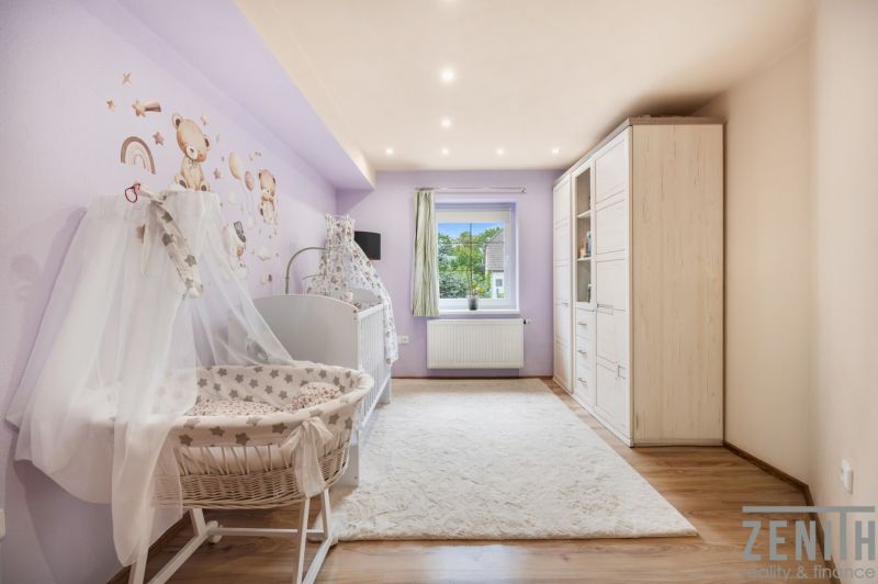 Children's room with pastel walls, a crib, and a wooden decor floor.
