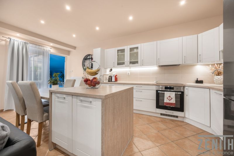 A kitchen in a family house with an island, white cabinets, and dining area.