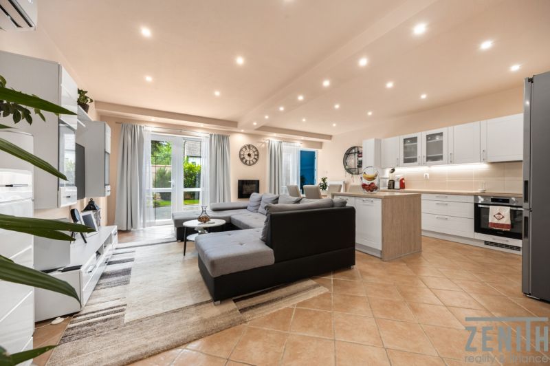 Living room with kitchen in a family house, light floor, large sofa.