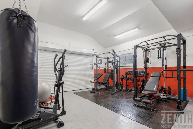 Home gym with exercise equipment, including a treadmill and a punching bag.