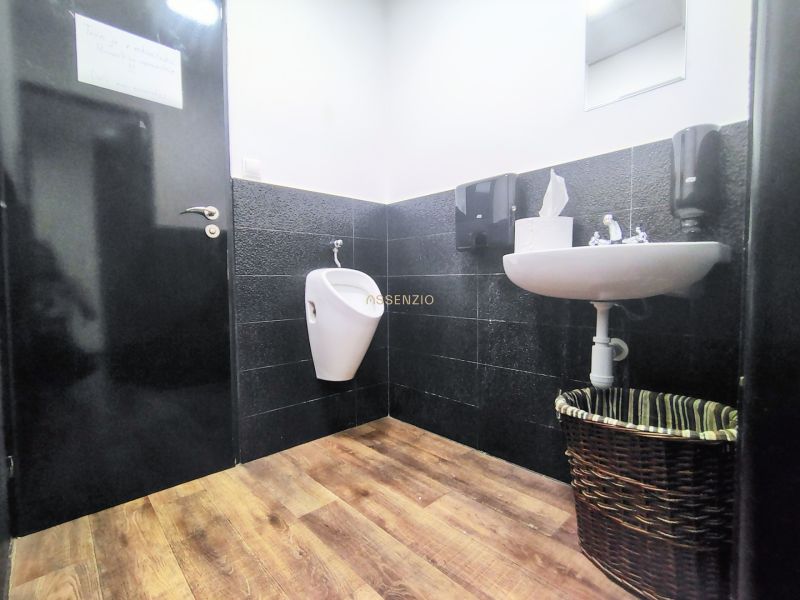 Restroom in the gastro area with a sink, urinal, and floor with a wooden decor.