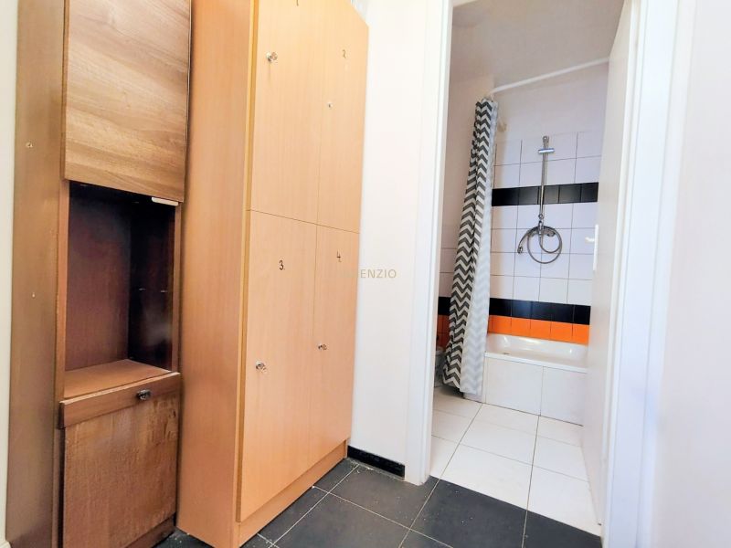 Bathroom in gastro premises with white tiles and a black and white curtain.