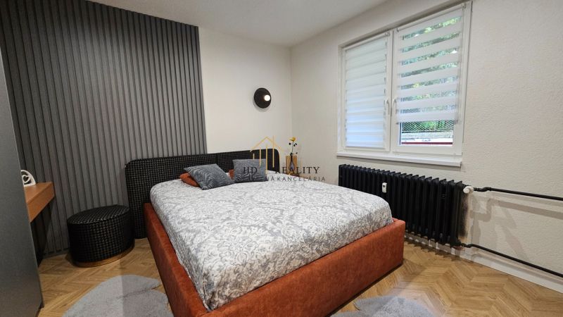 Bedroom in a 2-room apartment with a wood-patterned floor and a striped wall.