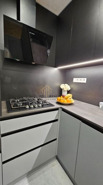 A kitchen in a 2-room apartment with a dark kitchen unit and a gas stove.