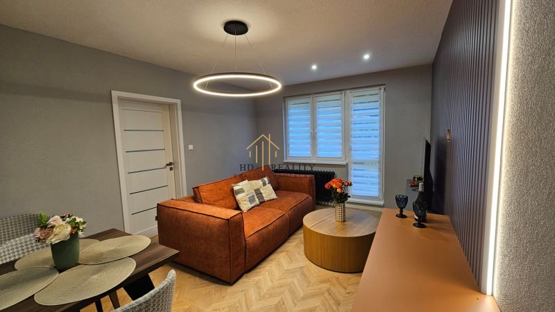 2-room apartment with an orange sofa and a round table, floor with wooden decor.