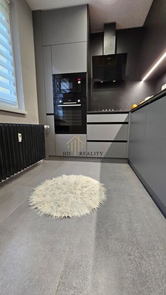 A stylish kitchen in a 2-room apartment with modern appliances and a round rug.